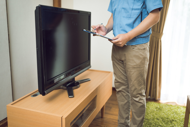 壊れたテレビの状態を確認する査定員