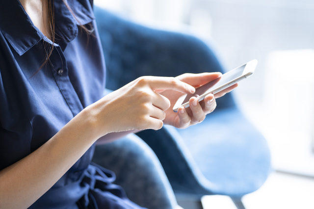 衣替えの服の処分方法をスマホで検索している女性