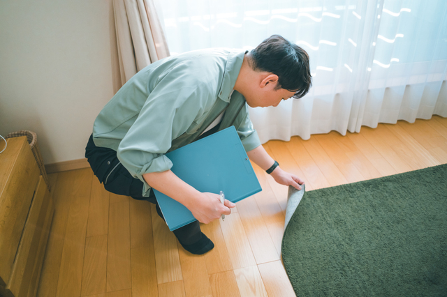 絨毯を裏返して結び目の密度を確認する査定士