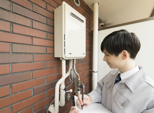 給湯器の型番と製造年式を確認する査定員