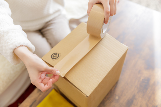 段ボールに小物やブランド品を詰めて発送の準備をしている様子